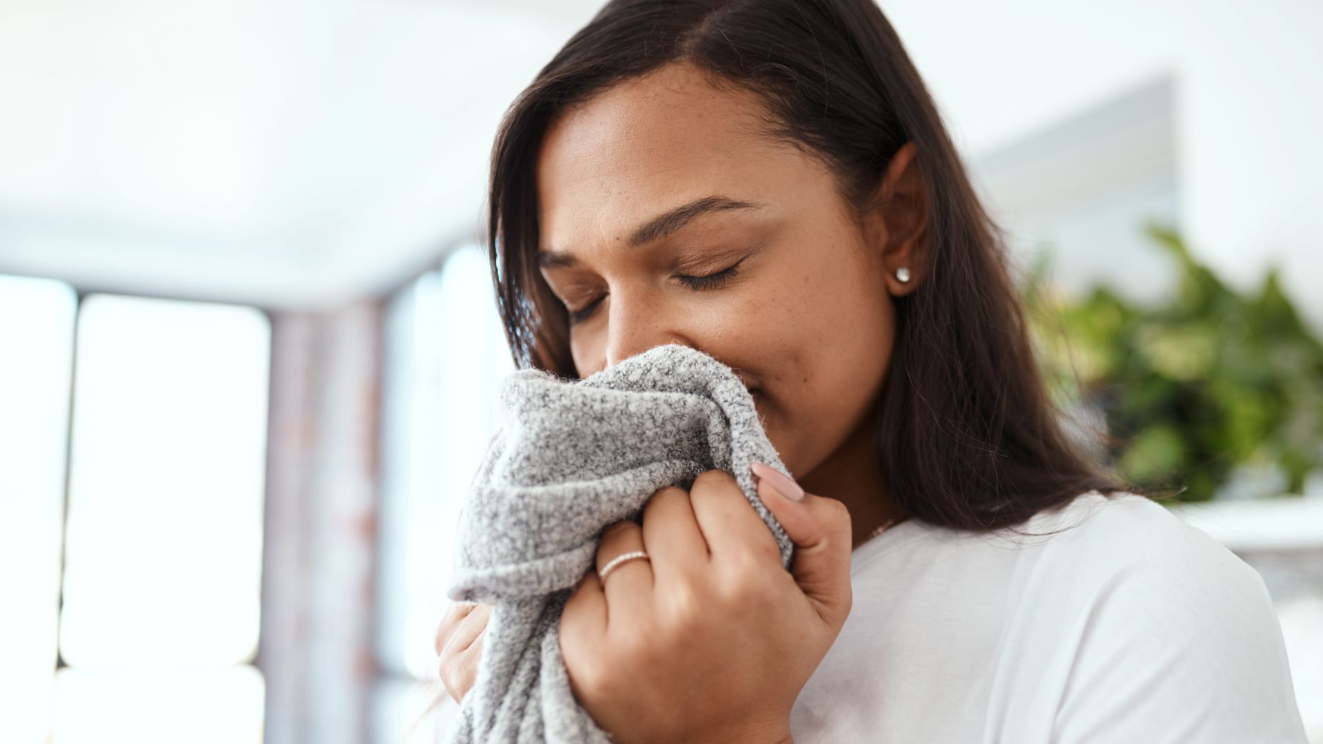  一位女士正在聞一條灰色毛巾