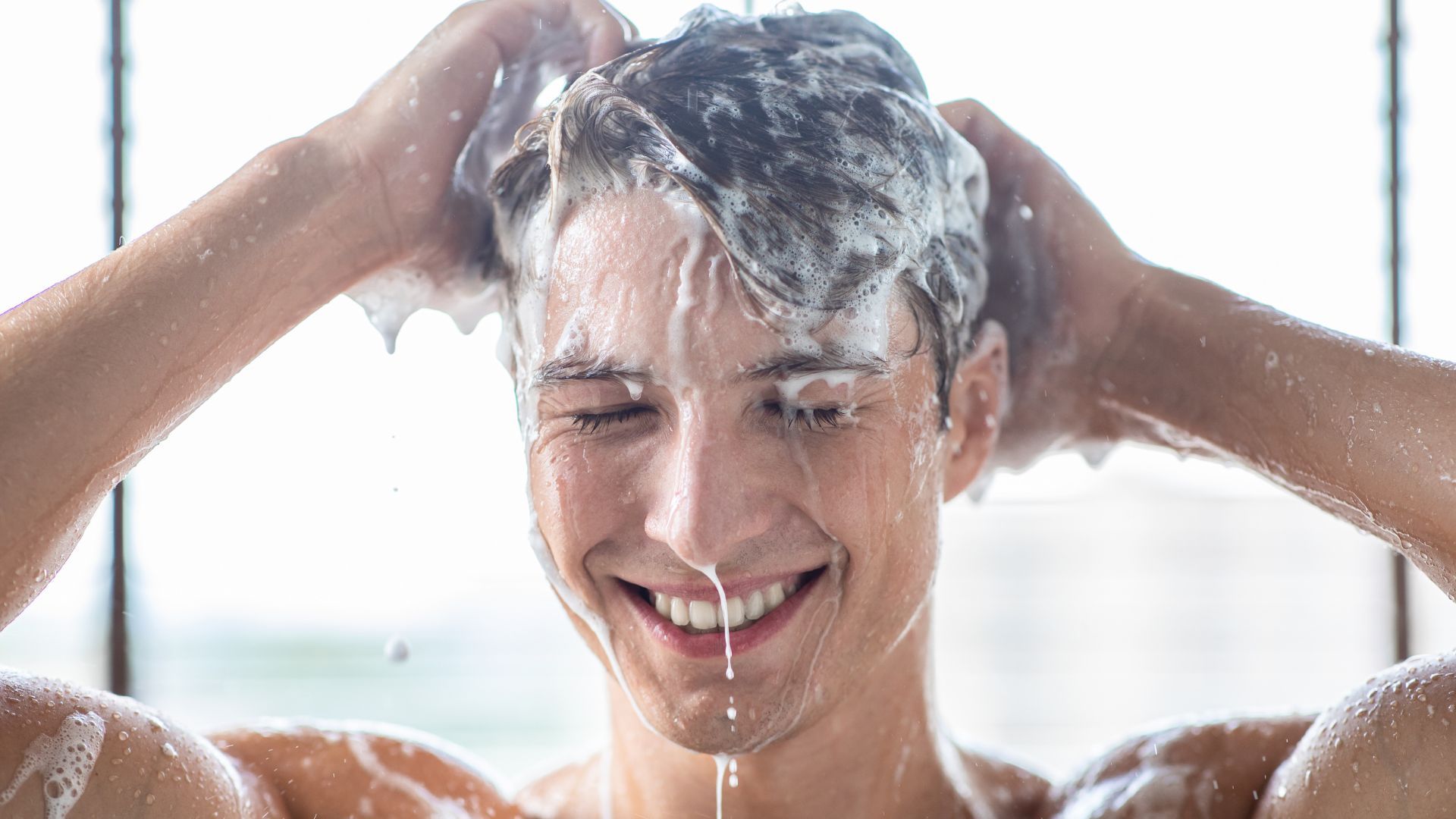 微笑的人正在用洗发水洗头。