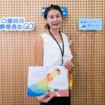 身着职业装的女子在品牌展示墙前展示一本插画儿童书。