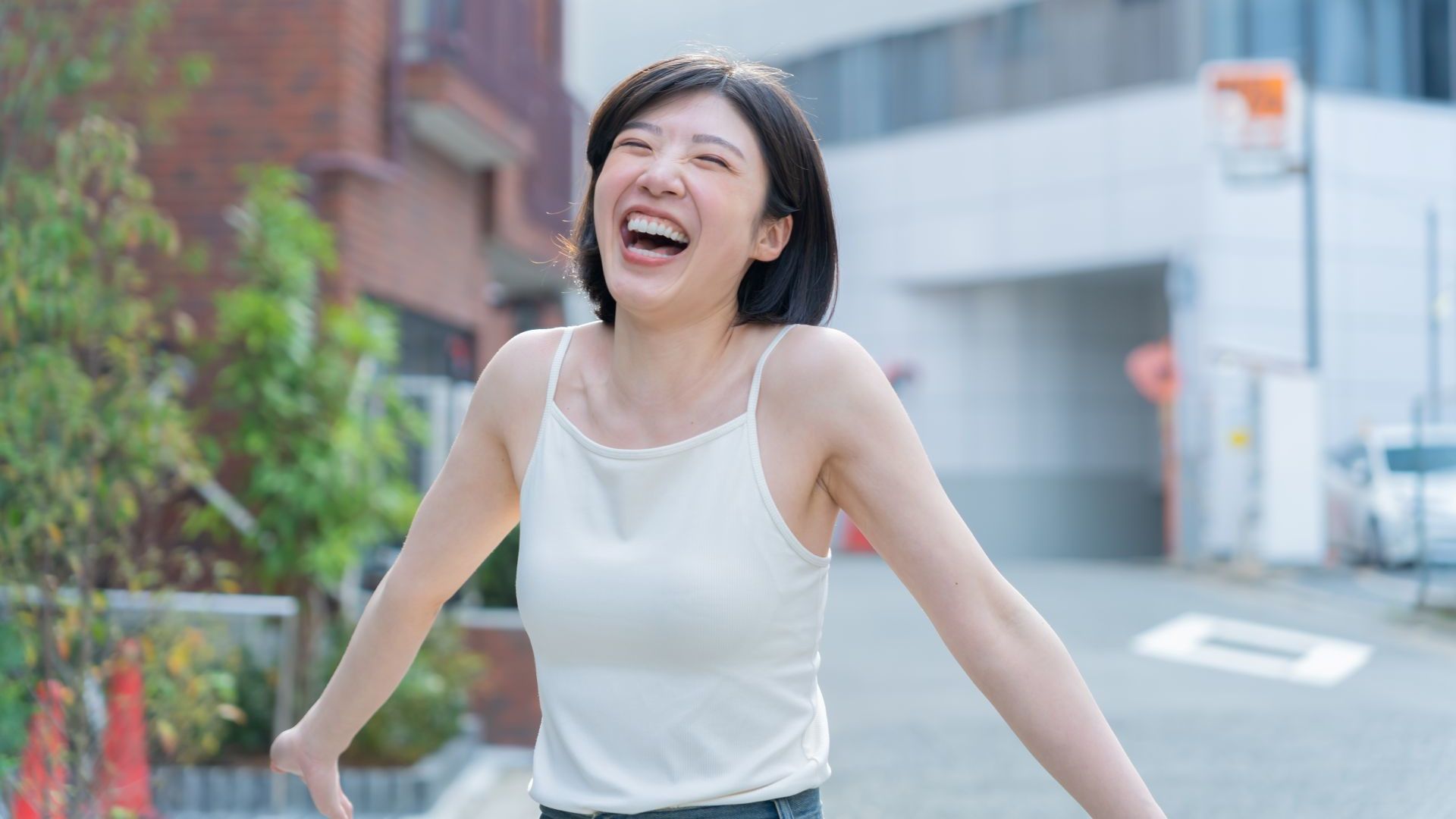 城市裡一位快樂的女士穿著白色無袖上衣。